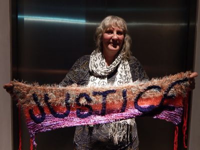 Caroline Kuyper with one of her yarn bombs (knitted slogans)!